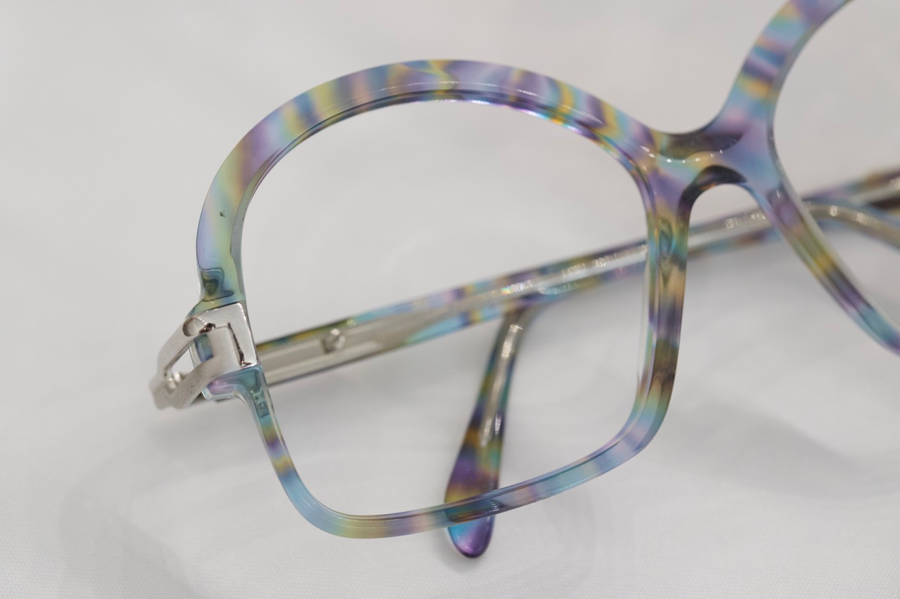 A pair of funky vintage eyeglasses that have a purple, yellow, and green pattern. 