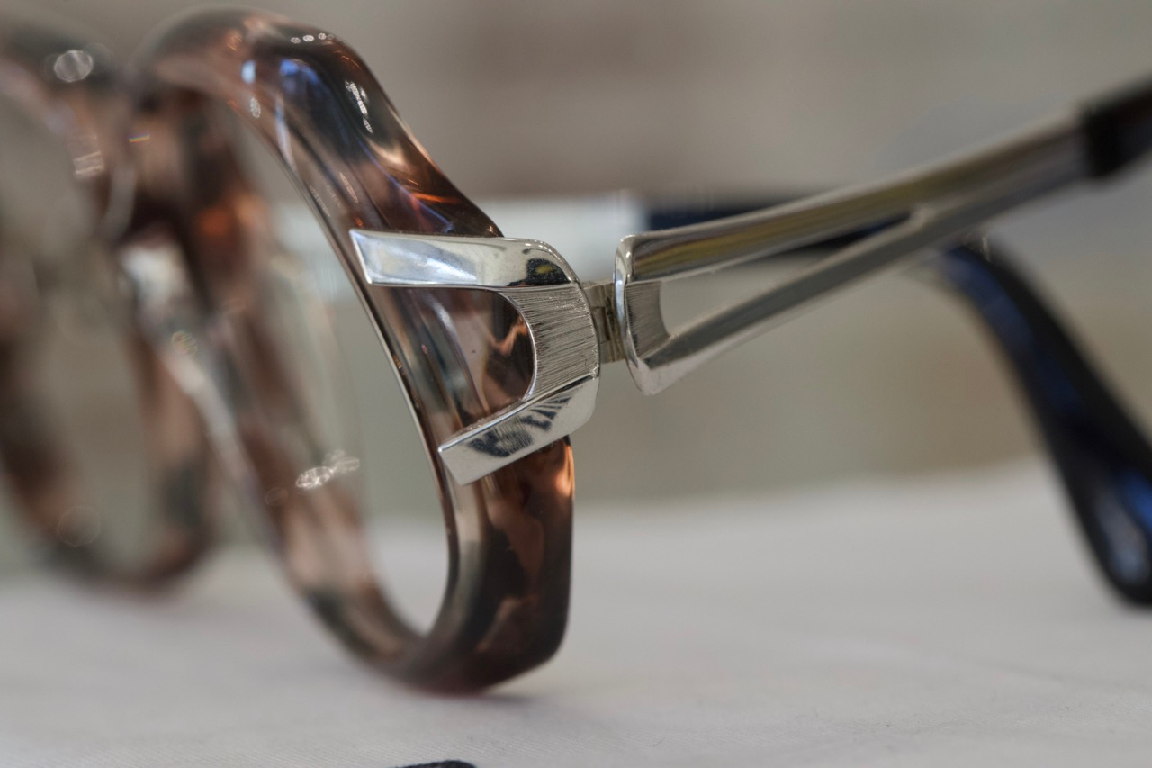 A pair of vintage eyeglasses with a tortoise shell frame with silver details. 