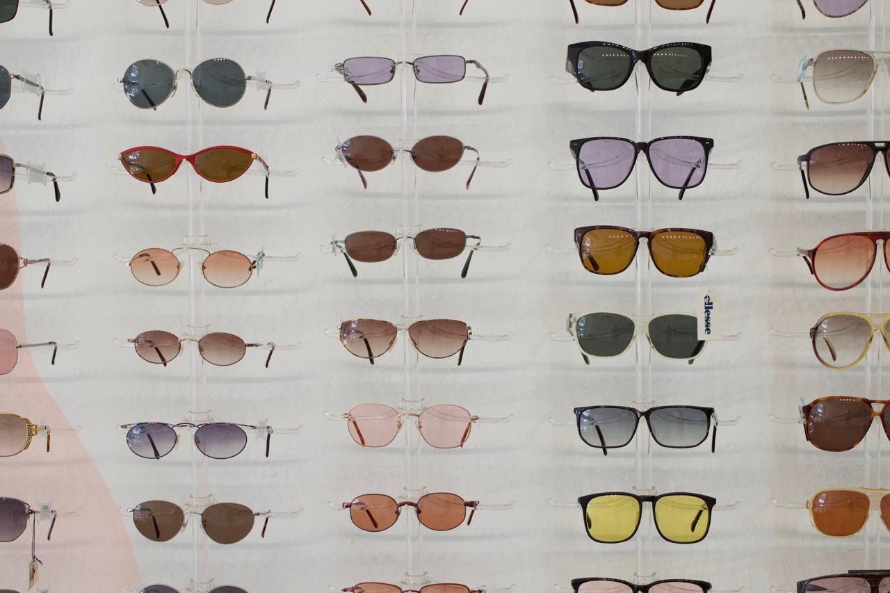 A wall display of sunglasses with different colored lenses. 